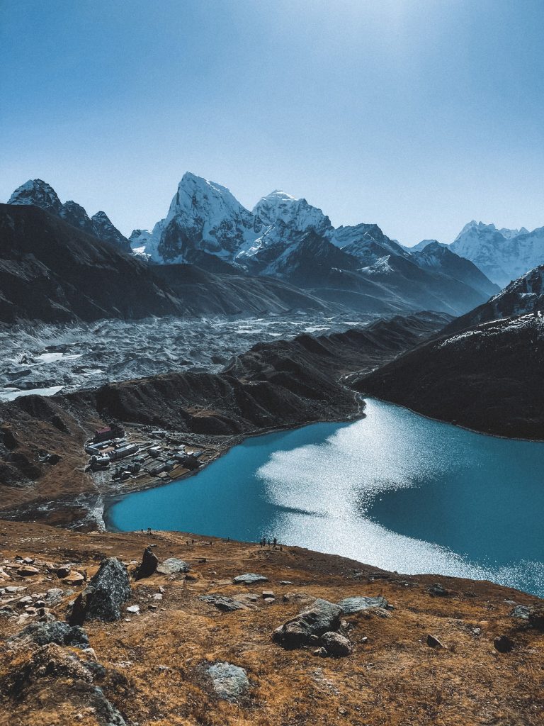 Breathtaking view of a calm blue lake surrounded by majestic snow-capped mountains in the Himalayas.